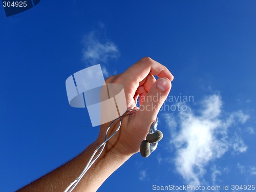 Image of Hand with small headphones on a background of the blue sky