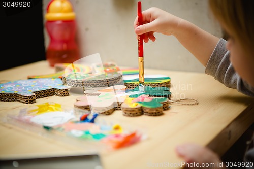 Image of Little female baby painting with colorful paints