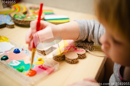 Image of Little female baby painting with colorful paints