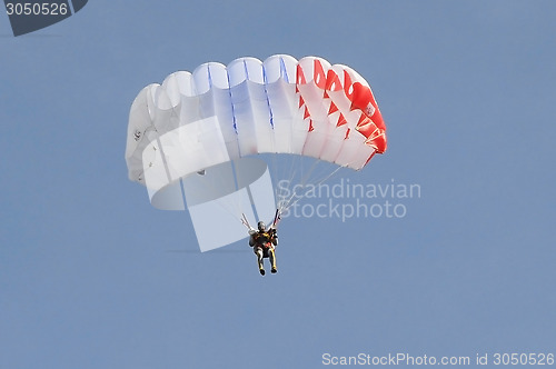 Image of The parachutist goes down on a multi-colored parachute.