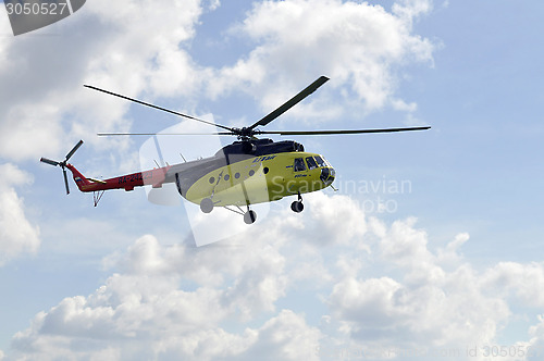 Image of The small yellow helicopter in the sky.