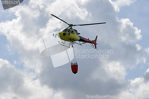 Image of The small yellow helicopter in the sky.