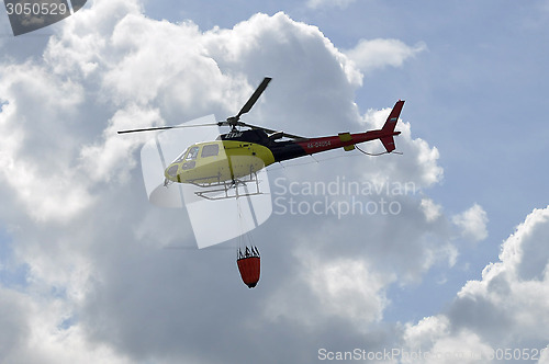 Image of The small yellow helicopter in the sky.
