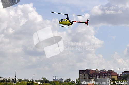 Image of The small yellow helicopter in the sky.