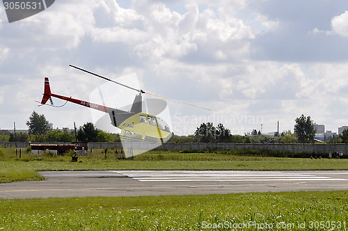 Image of The small yellow helicopter in the sky.