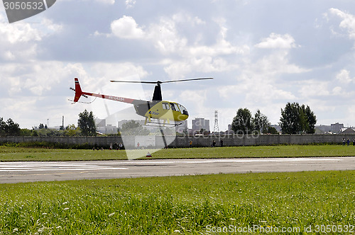 Image of The small yellow helicopter in the sky.