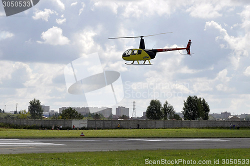 Image of The small yellow helicopter in the sky.