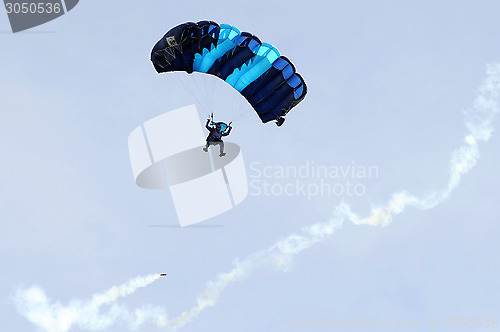 Image of the parachutist goes down on a multi-colored parachute.