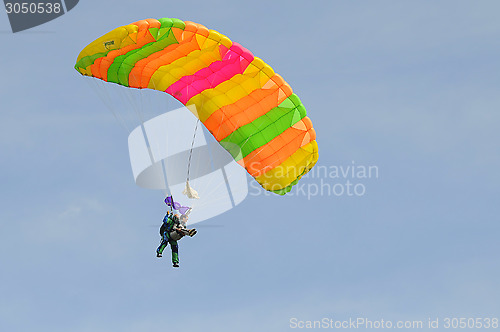 Image of the parachutist goes down on a multi-colored parachute.