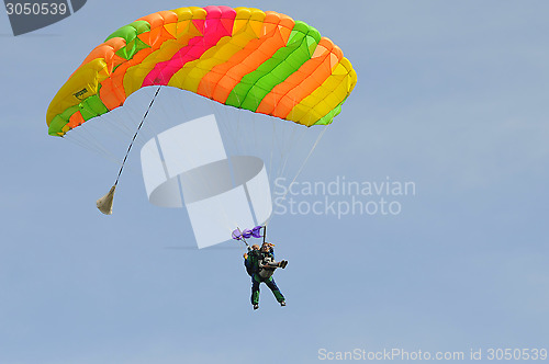 Image of the parachutist goes down on a multi-colored parachute.