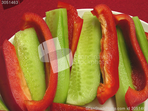 Image of Slitted red pepper and cucumber on a white plate and placemat