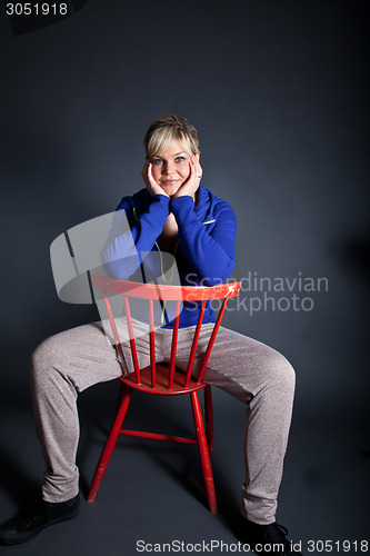 Image of Studio portrait of a cute blond girl sitting on a red chair