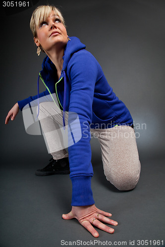 Image of Studio portrait of a cute blond girl one knee on the floor looki