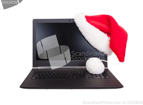 Image of Modern open laptop with red santa claus hat put on lcd corner