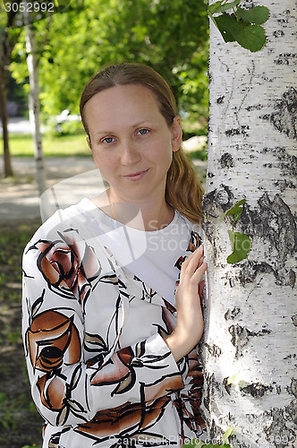 Image of The woman's portrait in park near a birch.