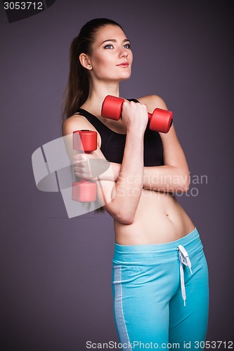 Image of Portrait of young woman with dumbbells