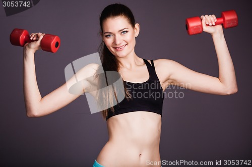 Image of Portrait of young woman with dumbbells