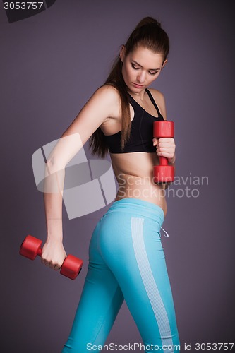Image of Portrait of young woman with dumbbells