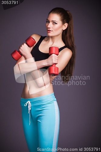 Image of Portrait of young woman with dumbbells