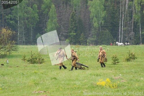 Image of soldiers with Maxim machine gun walk on field