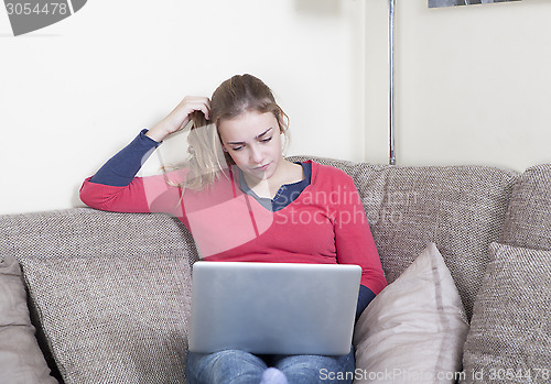 Image of Young woman with laptop on sofa