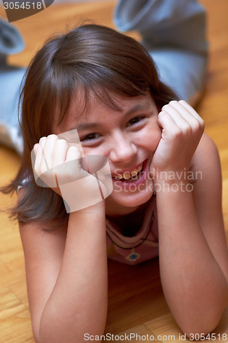 Image of smiling girl lying on the floor resting his head in hands