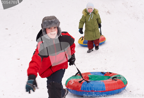 Image of boy and girl having fun pull snow tube up