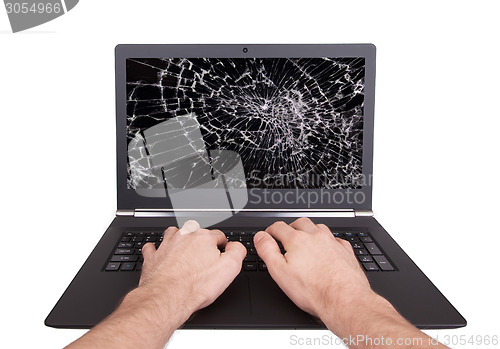 Image of Man working on a laptop with a broken screen