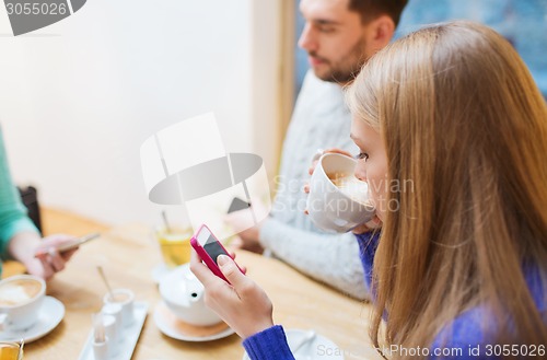Image of couple with smartphones drinking tea