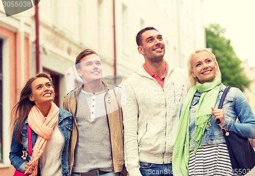 Image of group of smiling friends walking in the city