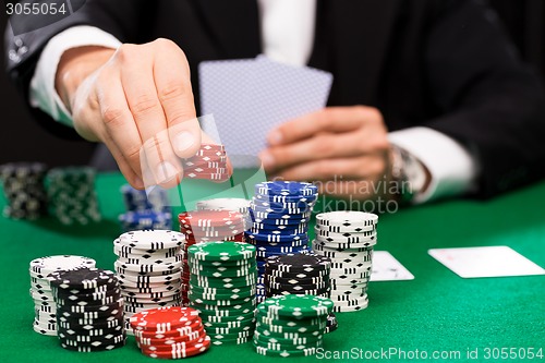 Image of poker player with cards and chips at casino