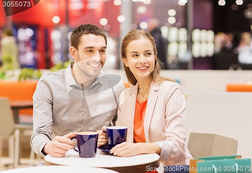 Image of happy couple with shopping bags drinking coffee