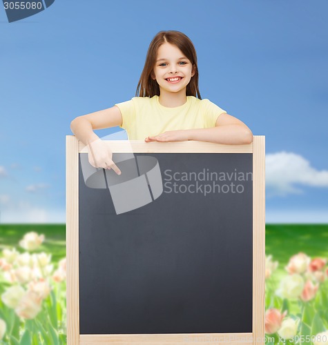 Image of happy little girl pointing finger to blackboard