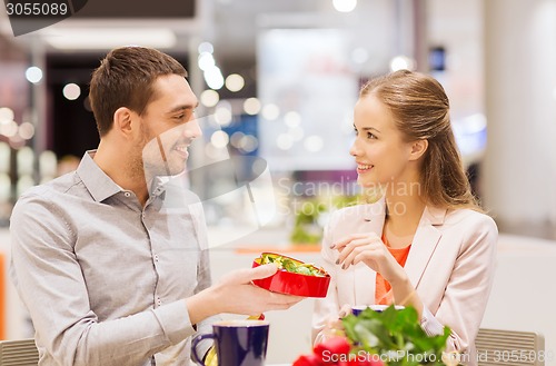 Image of happy couple with present and flowers in mall