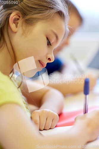 Image of close up of school kids writing test in classroom
