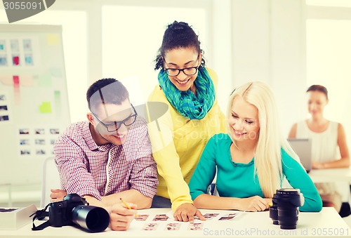 Image of smiling team with printed photos working in office