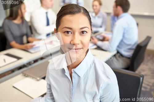 Image of group of smiling businesspeople meeting in office