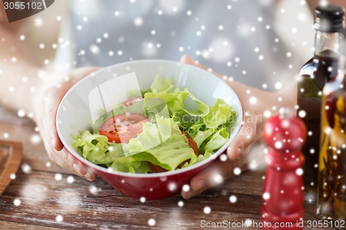 Image of close of male hands holding bowl with salad