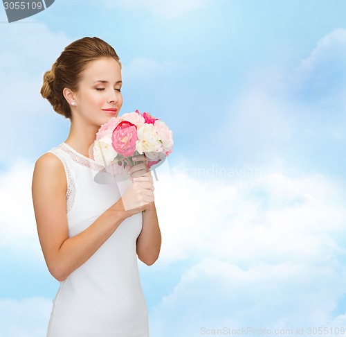 Image of smiling woman in white dress with bouquet of roses