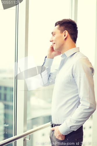 Image of smiling businessman with smartphone in office