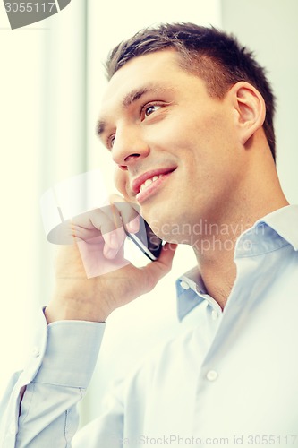 Image of smiling businessman with smartphone in office