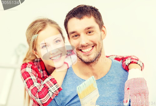 Image of smiling couple covered with paint with paint brush