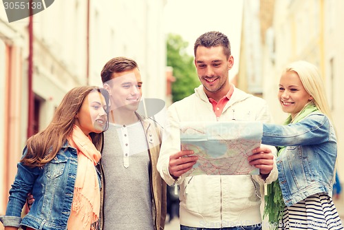 Image of group of smiling friends with map exploring city