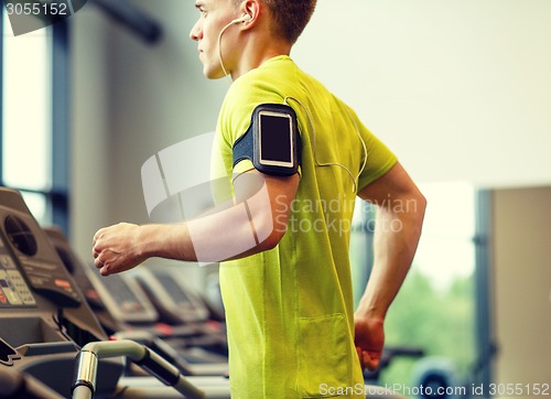 Image of man with smartphone exercising on treadmill in gym