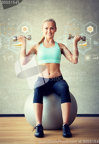 Image of smiling woman with dumbbells and exercise ball