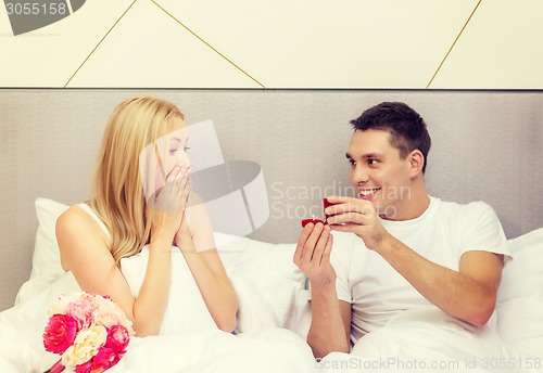 Image of man giving woman little red box and ring in it