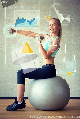 Image of smiling woman with dumbbells and exercise ball