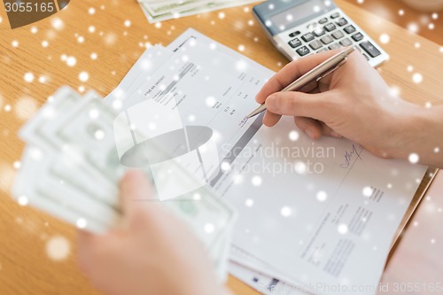 Image of close up of man counting money and making notes