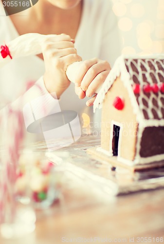 Image of close up of woman making gingerbread house at home