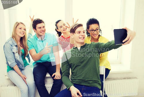 Image of smiling students making picture with tablet pc